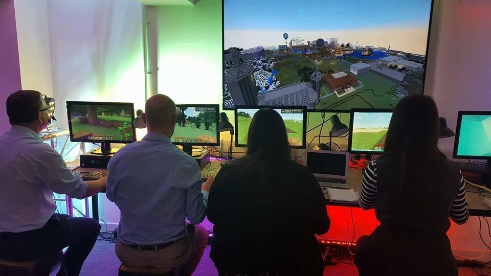 A group at a bank of monitors running a shared Minecraft world during a training session.