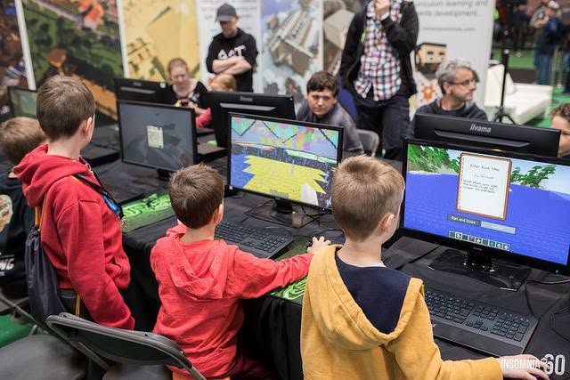 Children playing a Minecraft esports build battle on monitors at a live gaming event.